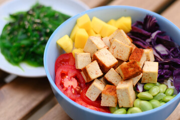 Tofu vegetarian poke bowl on wooden table