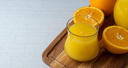 Glass and jug with orange juice on a wooden stand, sliced orange, background line
