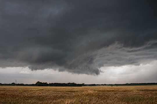 A wall cloud underneath a severe storm over a dry field in Kansas.