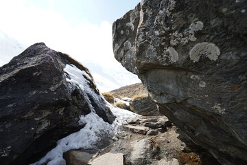 Rocky trail pathway with natural landscape view of snowcapped mountain range with cloudy blue sky- Himalayas ridge, Nepal