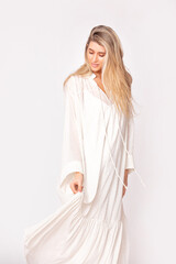 Portrait of a beautiful and young adult model of a blonde woman in a white dress on a white background. Studio shot.