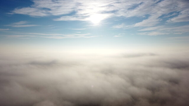 Aerial Drone View Flight Over Fog And Under Clouds With Shining Sun Shining. Fly Through Clouds. Amazing Beautiful Nature Landscape. Scenic Aerial View Moving White Clouds In Blue Sky. Seamless Loop.