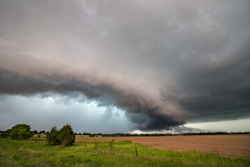 Naklejka na ściany i meble A shelf cloud and severe storm filled with rain and hail over a farm field in Kansas.