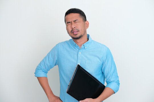 Adult Asian man holding a laptop showing exhausted gesture