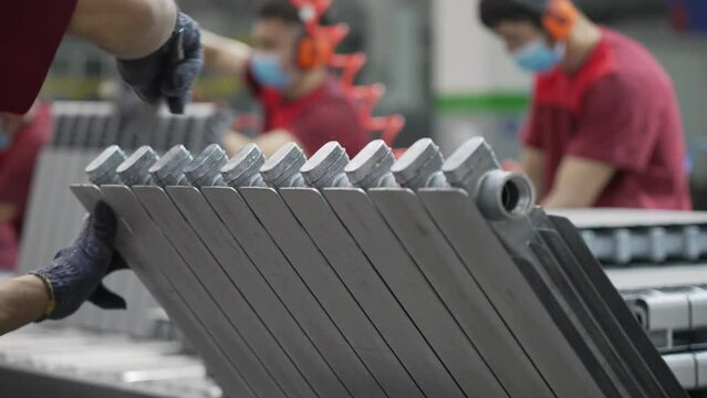 The worker processes the radiator part, removes the burr after casting, prepares it for further processing. Production of household radiators at the radiator manufacturing plant.