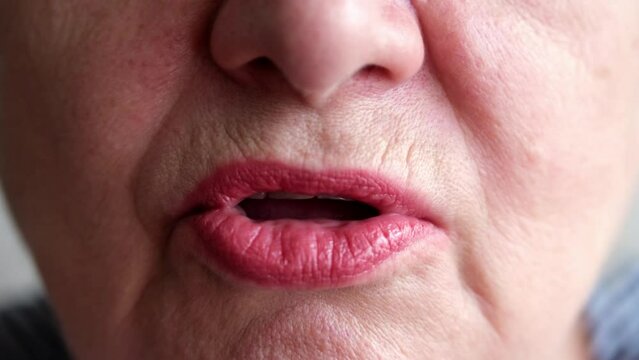 Close-up of a beautiful mature woman's lips. Lower face of an talking elderly woman. Slow motion