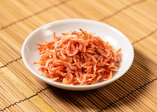 Dried sakura shrimps on a plate placed on a bamboo luncheon mat.