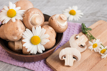 Fototapeta na wymiar Gray mushrooms are champignons in a basket. Decorated with field daisies