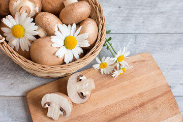 Gray mushrooms are champignons in a basket. Decorated with field daisies