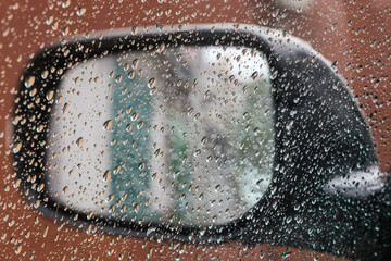 Inside view of car rearview mirror during rain, selective focus