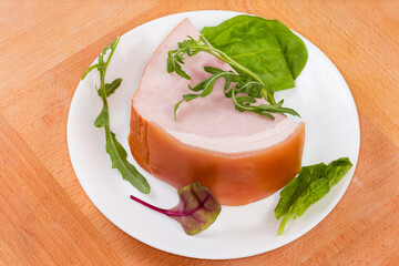 Piece of boiled smoked ham and greens on the dish