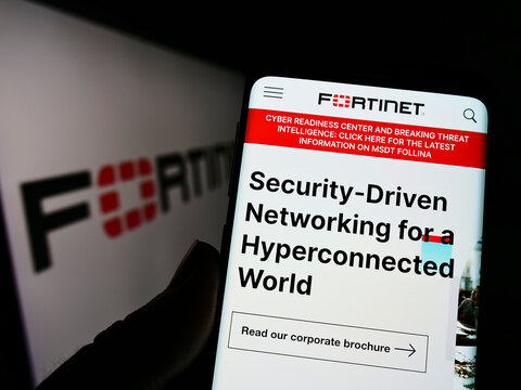 Stuttgart, Germany - 07-03-2022: Person holding cellphone with website of US cybersecurity company Fortinet Inc. on screen in front of logo. Focus on center of phone display.