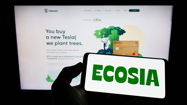 Stuttgart, Germany - 07-03-2022: Person holding mobile phone with logo of German search engine company Ecosia GmbH on screen in front of business web page. Focus on phone display.
