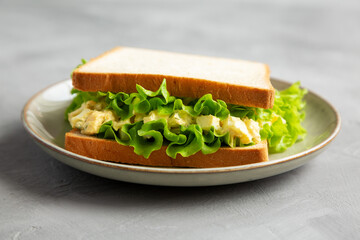 Homemade Egg Salad Sandwich with Lettuce on a Plate, side view.