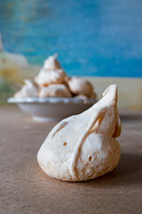 Homemade french milk-colored meringues on crumpled craft paper