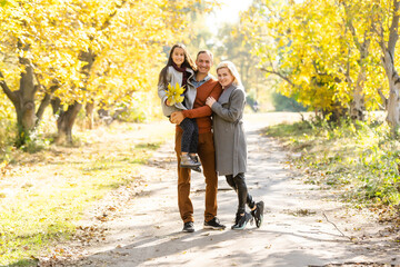Obraz premium Young happy family while walking in the autumn park.