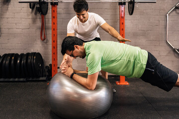 Personal trainer with a first-time trainee correcting habits in the exercise room. Personalized...