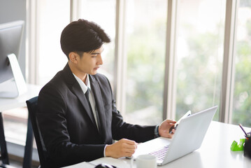 Business Asian man working using smart phone with smiling and confident emotion.