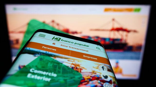Stuttgart, Germany - 01-29-2022: Mobile phone with webpage of Colombian banking company Banco Popular S.A. on screen in front of monitor. Focus on top-left of phone display.