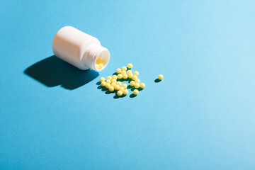 Ball pills and a white plastic bottle on blue background.