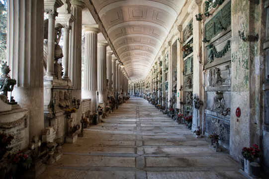 Staglieno, Genova, Italia - 22 giugno 2021: Cimitero monumentale..Prospettiva di galleria di cimitero monumentale. Le lapidi delle tombe si perdono in lontananza tra luci ed ombre.