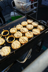 A view of a griddle cooking up several ramen noodle patties, using silicon ring molds to hold the noodles into shape.