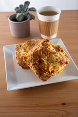 A view of a plate of scones and hot tea in a to-go cup.