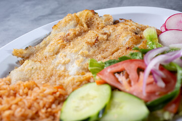 A view of a plate of deep fried tilapia filet.