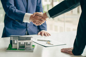 Sales agents and landlords when signing a contract to buy or rent a new home. Real estate agents shake hands with customers after signing contracts. Contract documents and house plans on a wooden tabl