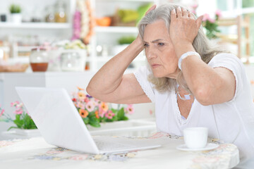 sad senior woman using laptop at home