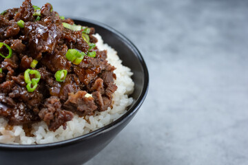 A closeup view of a teriyaki beef bowl, on the left side of the frame.