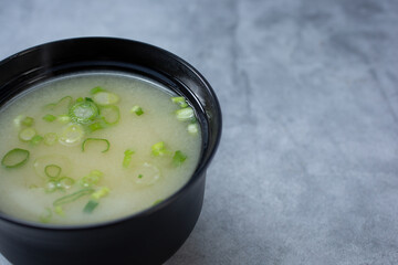 A view of a bowl of miso soup, on the left side of the frame.
