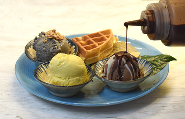 Homemade ice cream with waffle on plate with chocolate syrup