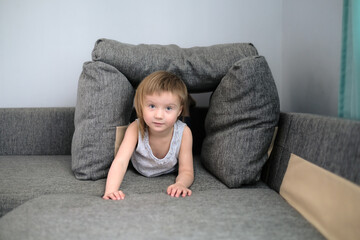 funny European child playing with pillows on couch