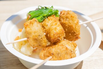 Battered hake brochette with vegetables on a white plate.