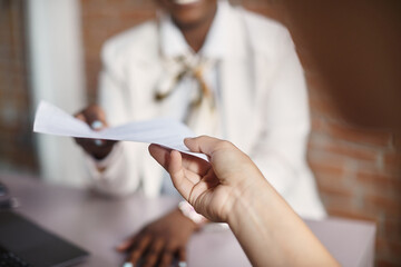 Close up of businesswoman takes CV from job candidate during meeting in office.