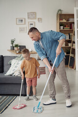Gay father teaching his adopted child to wash floor with mop during housework in the room