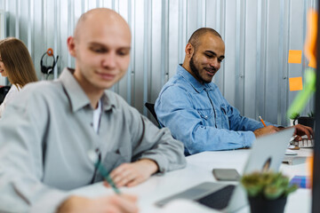 Obraz premium Young bald business man sitting at desk in office, working on computer