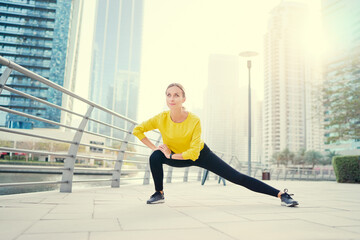 Fototapeta na wymiar Healthy lifestyle. Young woman exercising on city embankment.