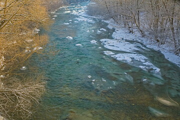 In winter, the unfrozen riverbed in the snow-covered banks. winter background