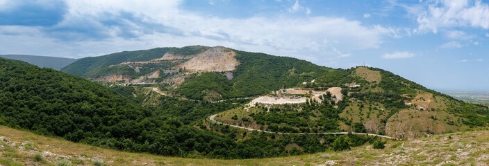 Panorama on quarry for extraction of minerals with equipment and machines and road, in Rhodope...