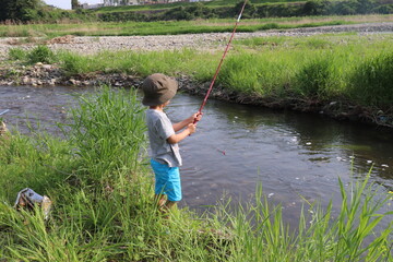 田舎の小川で初めての釣りをする小さな男の子