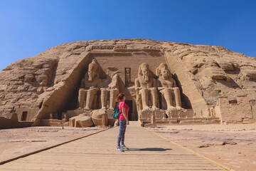 White Woman Tourist in front of the Colossal Statues of Ramesses II seated on a throne near the...