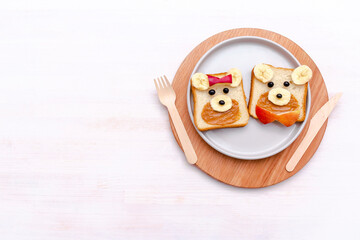 Funny cute bear,dog faces sandwich toast bread with peanut butter, banana and apple. Kids childrens baby's sweet dessert healthy breakfast lunch food art on plate,white background close up,top view