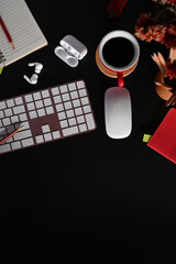 Black wooden office with wireless keyboard, coffee cup, earphone and flower pot