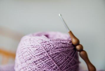 Women's hobby is knitting. Yarn of warm purple tones. A ball of thread and a hook.