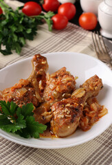 Baked chicken drumsticks with vegetables, spices and parsley on white plate