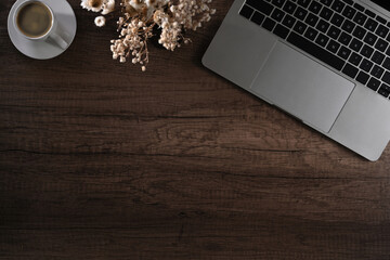 Simple workspace with laptop computer, flower pot and coffee cup on wooden table