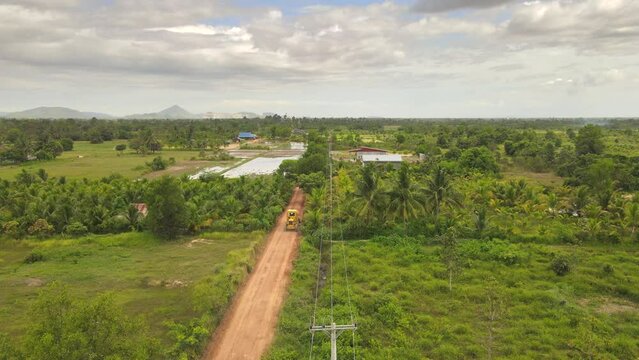 aerial drone footage of a road grader widening side of the rural road in the countryside 