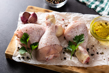 Raw chicken meat legs with spices and herbs on black background	